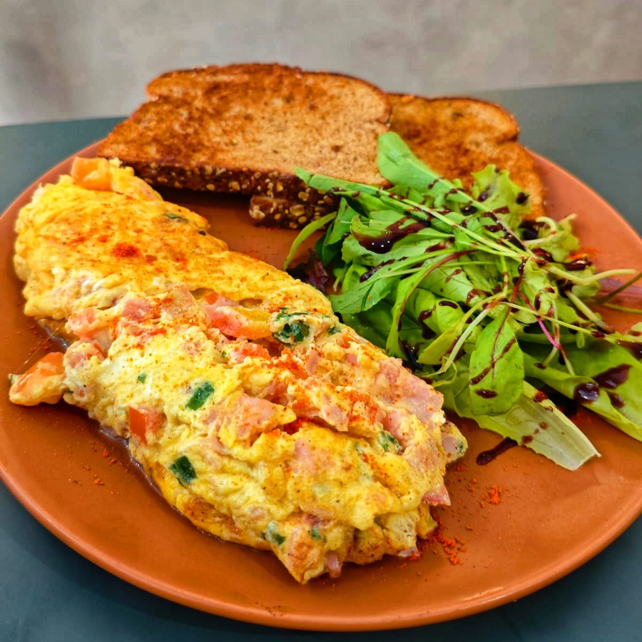 3 ovos, tomate, mussarela, presunto, cheiro verde e manteiga. Acompanha pão na chapa e mini salada.