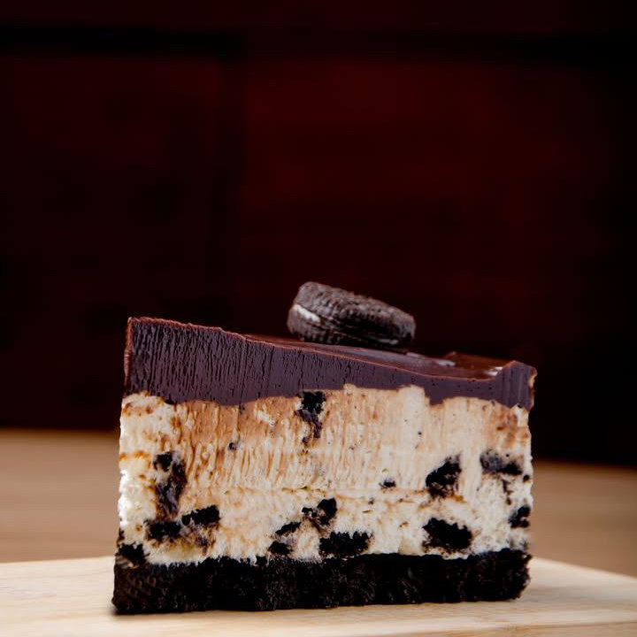 Uma fatia de torta mousse de oreo com massa de biscoito oreo, mousse de oreo e cobertura de chocolate