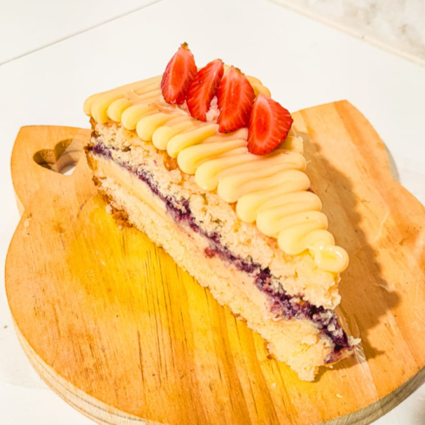 Esse sabor vai te surpreender. Essa fatia é composta por uma massa de limão siciliano bem macia e úmida, recheado com um cremoso brigadeiro de limão siciliano, e uma geleia artesanal de frutas vermelhas. O cítrico que equilibra tudo, não deixando enjoativo. Vale a pena experimentar.