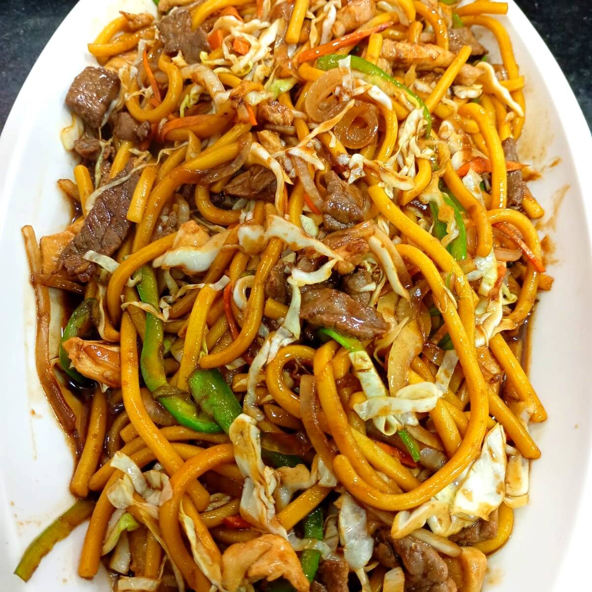 Carne, Frango, Legumes fatiados, Repolho, Cenoura, Cebola, Pimentão, a base de molho shoyu e Temperos do Chef