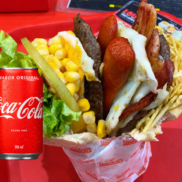 Hambúrguer Completo com Bacon, Salsicha, Ovo, Presunto, Mussarela, Tomate, Alface, Milho e Batata Palha. Acompanha Coca-Cola 350ml pra Combinação Perfeita!