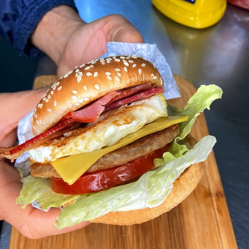 Pão tradicional com cereal de gergelim, carne de 56g suculenta e macia, bacon, alface e tomate, ovo no ponto, queijo derretendo sobre a carne e molho Gourmezi. Acompanha maionese temperada. .