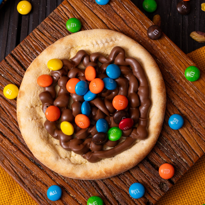 Feita para você sorrir ao abrir a caixa. A Esfiha mais divertida do Bedu é feita com um cremoso chocolate coberto por coloridos M&Ms. O suave e macio do recheio se mistura com o crocante da massa e do M&M, fazendo dessa esfiha uma explosão de sabores que vão te levar de volta a magia da infância.