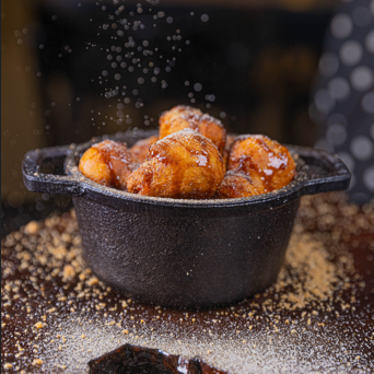 Sabe aquela receita tradicional de vó, então, imagina fazer uma releitura do bolinho de chuva com pedacinhos de bacon enrolados no açúcar e canela regados no melaço de cana