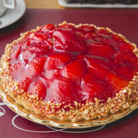 Deliciosa torta de morango com base crocante, creme suave e morangos fresquinhos por cima, finalizada com uma camada delicada de geleia que dá brilho e sabor irresistível.