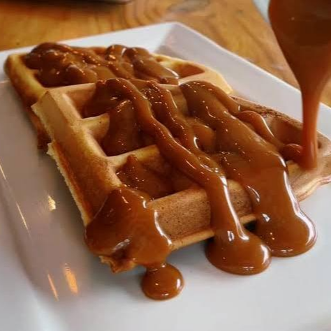 Waffle dourado e macio, servido com calda de doce de leite.
