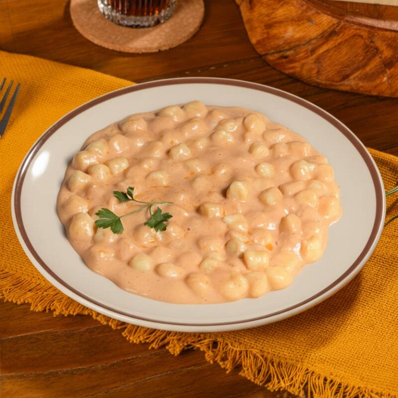 Nhoque de batata com molho rosé e queijo derretido.