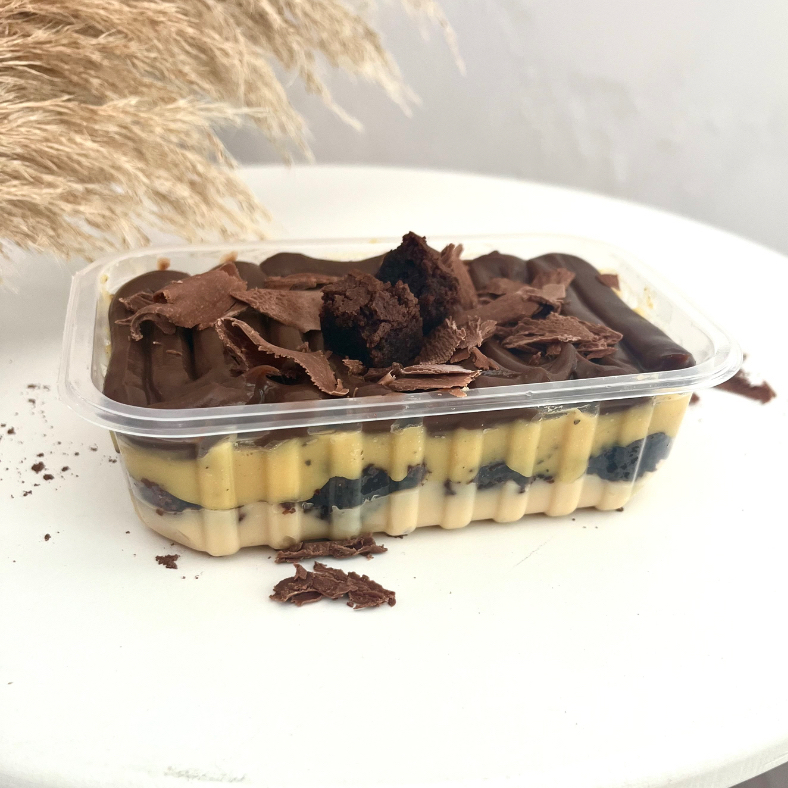 Nosso escondidinho de maracujá é imperdível! Brigadeiro de ninho na base, uma camada do nosso suculento brownie, outra generosa camada de brigadeiro de maracujá feito com geleia da fruta, finalizado com brigadeiro de chocolate blend e raspas de chocolate.