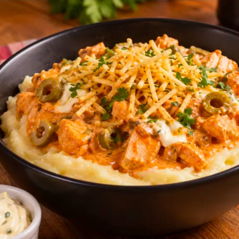 Nossa batata em formato de purê, cremosa e saborosa, coberta com estrogonofe de frango, requeijão cremoso de alta qualidade e azeitonas. Acompanha batata palha crocante e nossa maionese temperada.