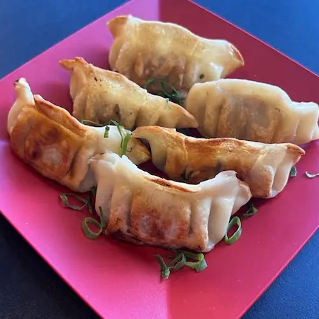 Pastéis recheados com carne de porco temperada e vegetais, cozidos no vapor e levemente grelhados.