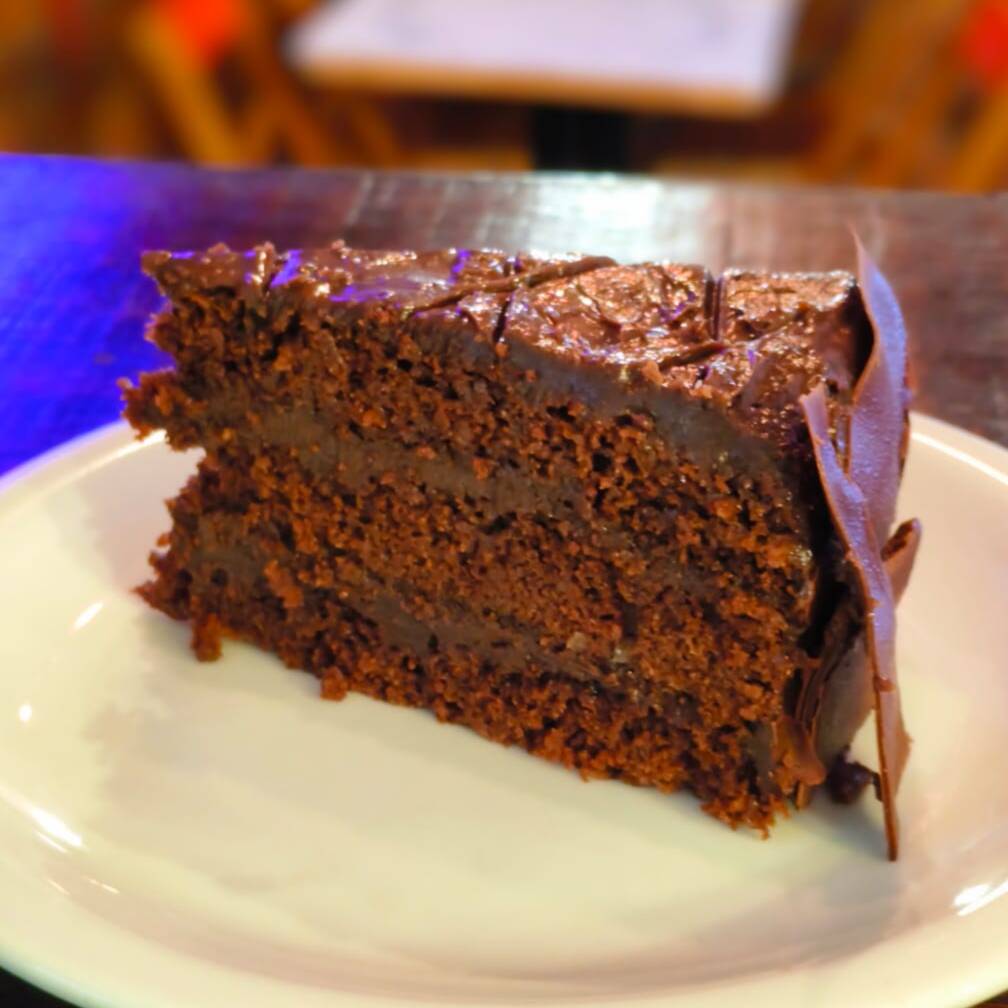 Fatia generosa de torta com massa macia de chocolate, recheio cremoso em camadas e cobertura intensa de chocolate. Uma sobremesa irresistível para os apaixonados por chocolate.