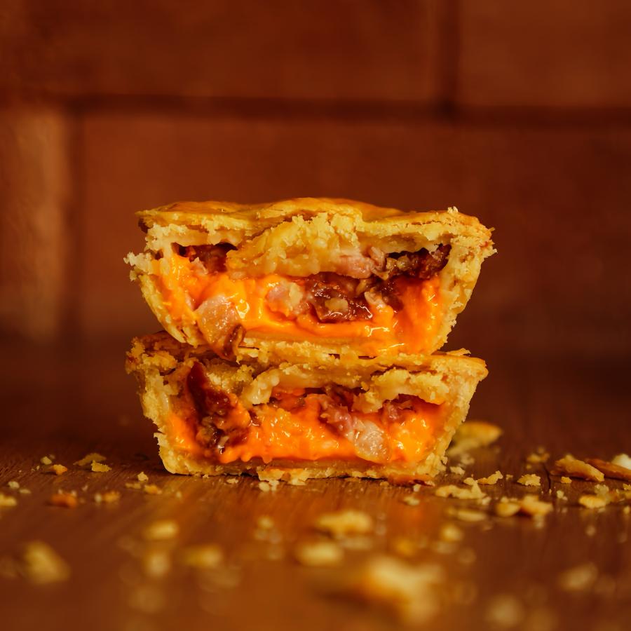 Cheddar cremoso de verdade com bacon em cubos, derretendo dentro da nossa massa alta e dourada. Indulgência pura.