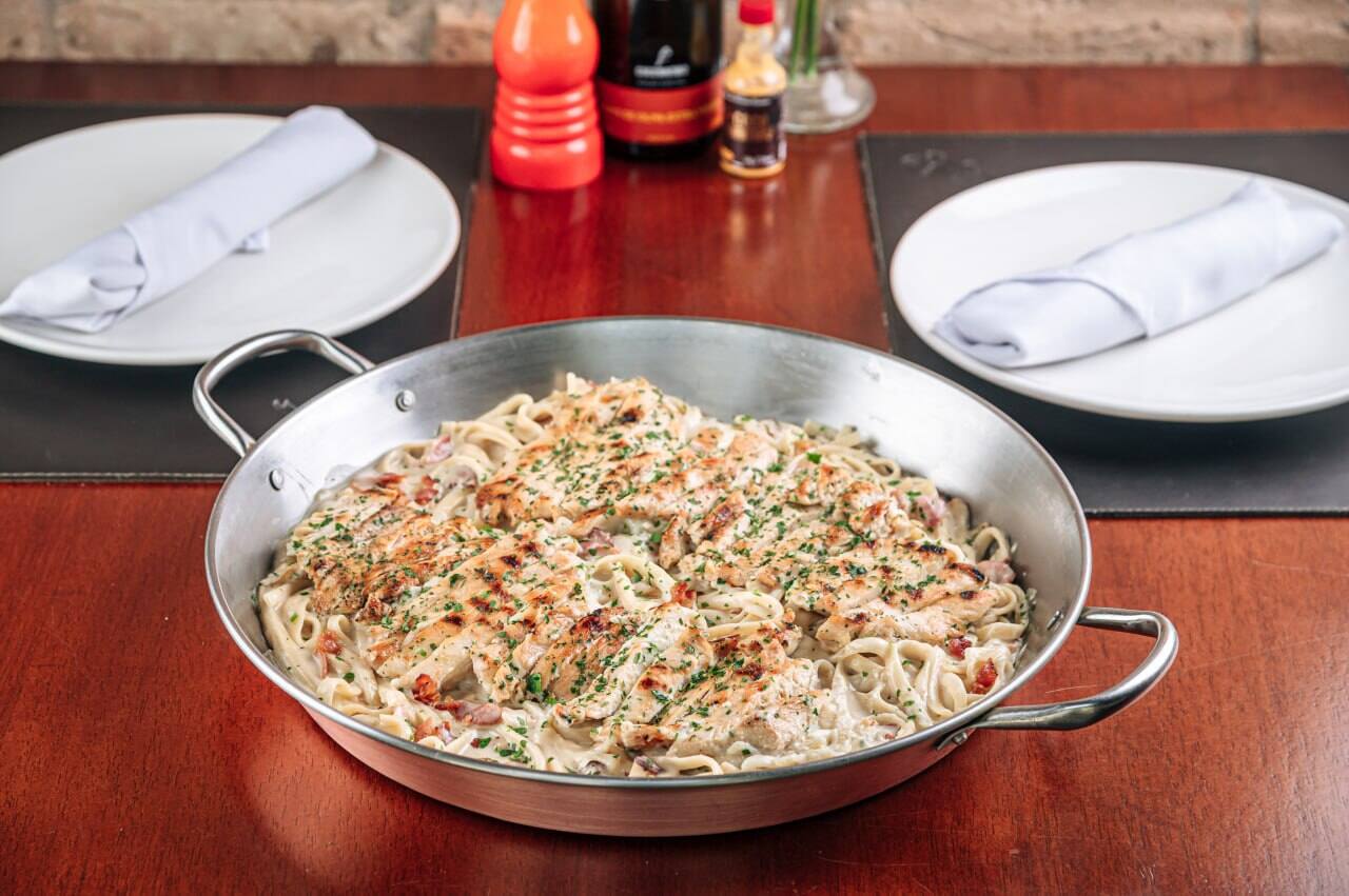 Filé de peito de frango grelhado sobre fettuccine com molho alfredo e bacon.