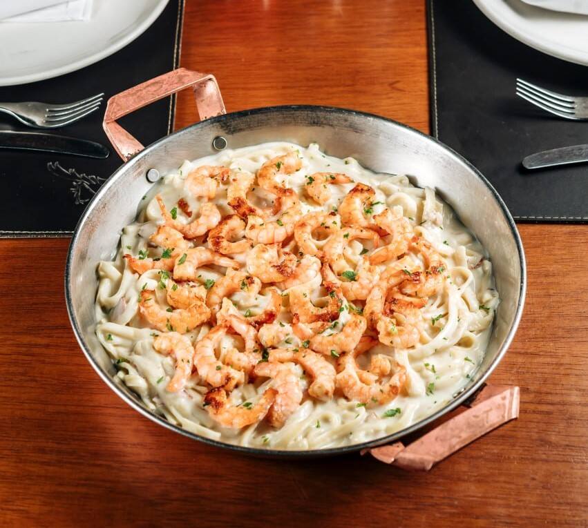 Camarão grelhado sobre fettuccine com molho alfredo e bacon.