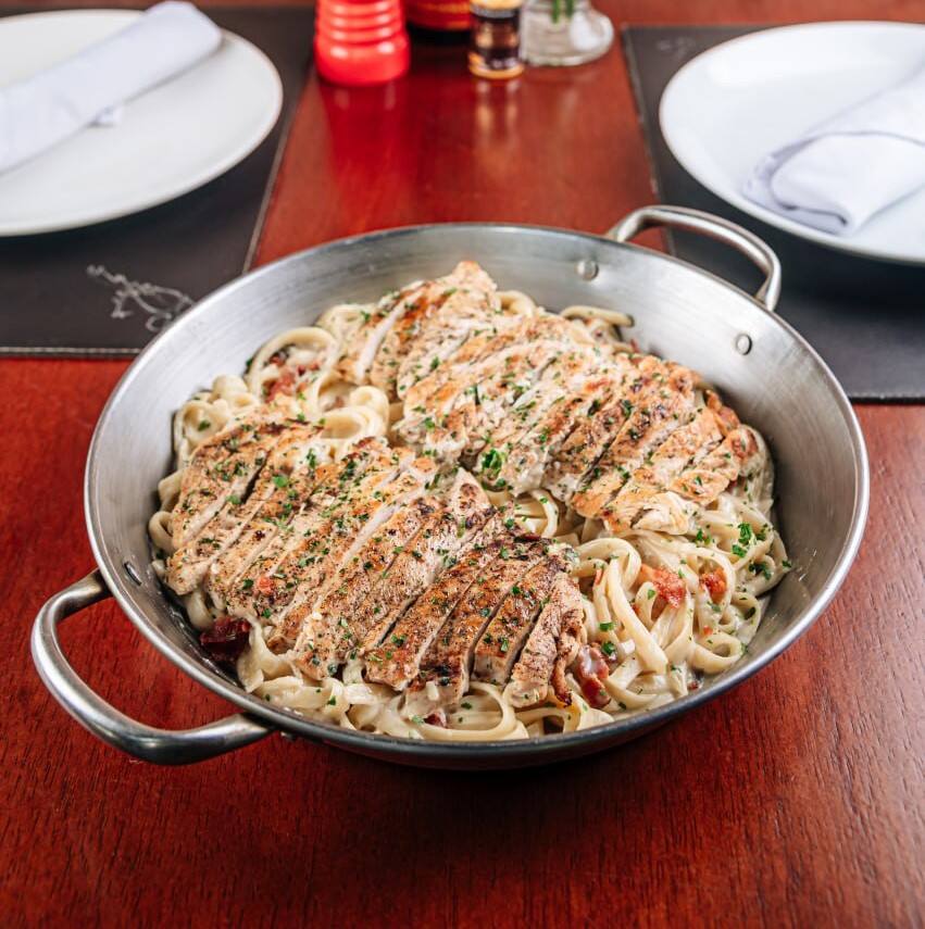 Filé de peito de frango grelhado sobre fettuccine com molho alfredo e bacon.