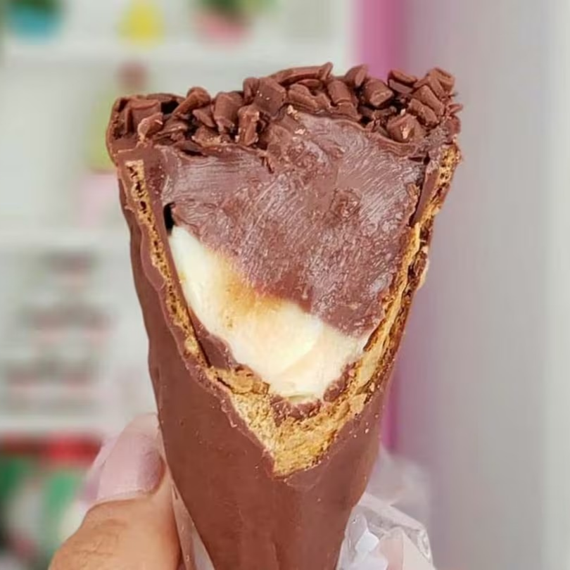 Delicioso cone de waffle banhado em chocolate ao leite com recheio a sua escolha.