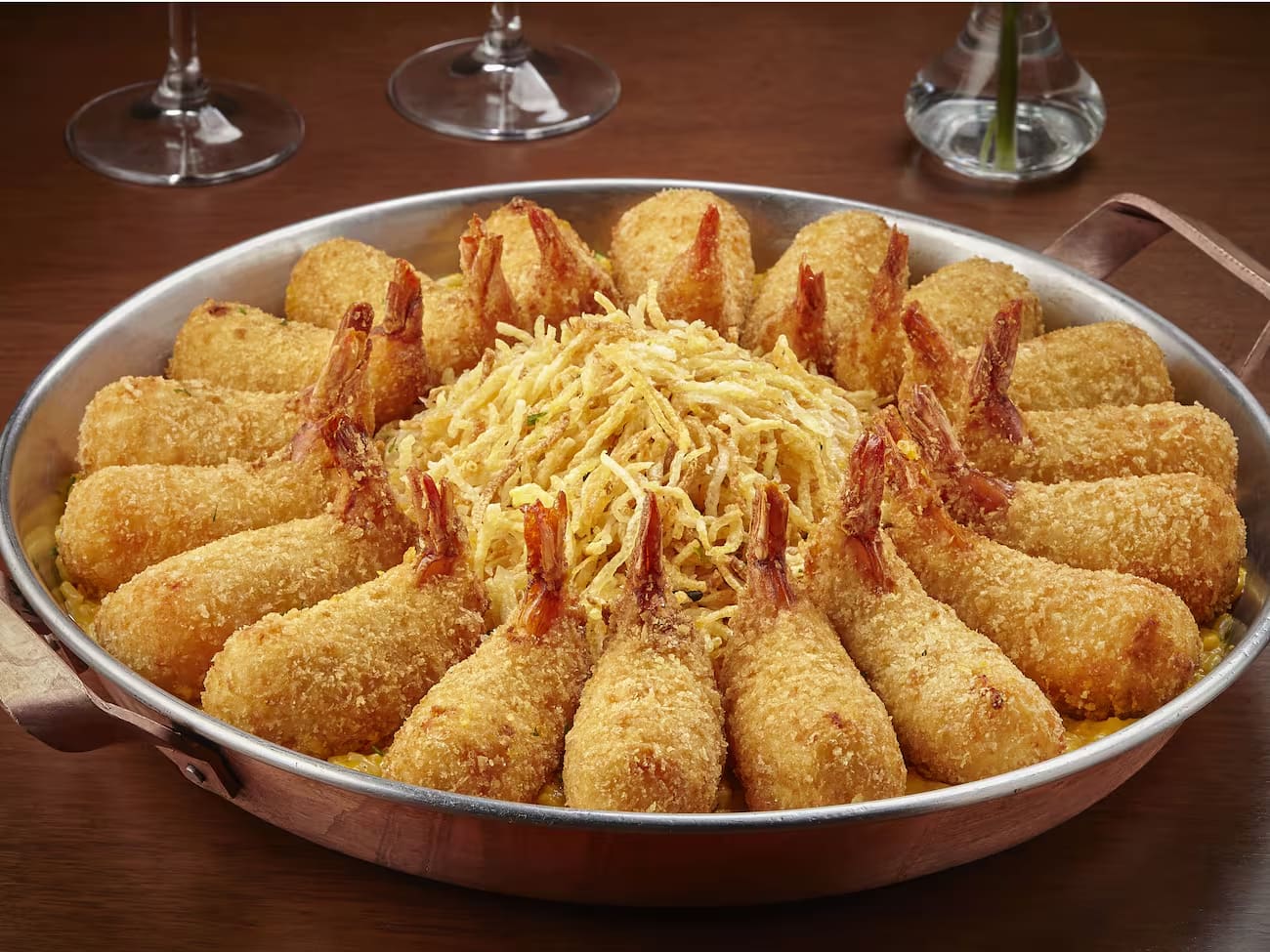 18 camarões empanados e recheados com Catupiry, sobre um cremoso arroz de moqueca com camarõees e coentro, coberto com batata palha. Acompanha farofa de panko com bacon e alhoporó.