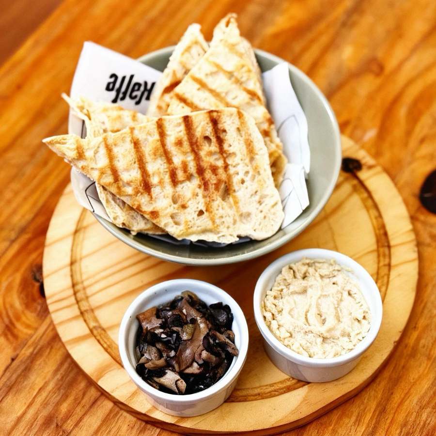 Pão ciabatta de fermentação natural com porção de homus e mix de cogumelos. Vegano.