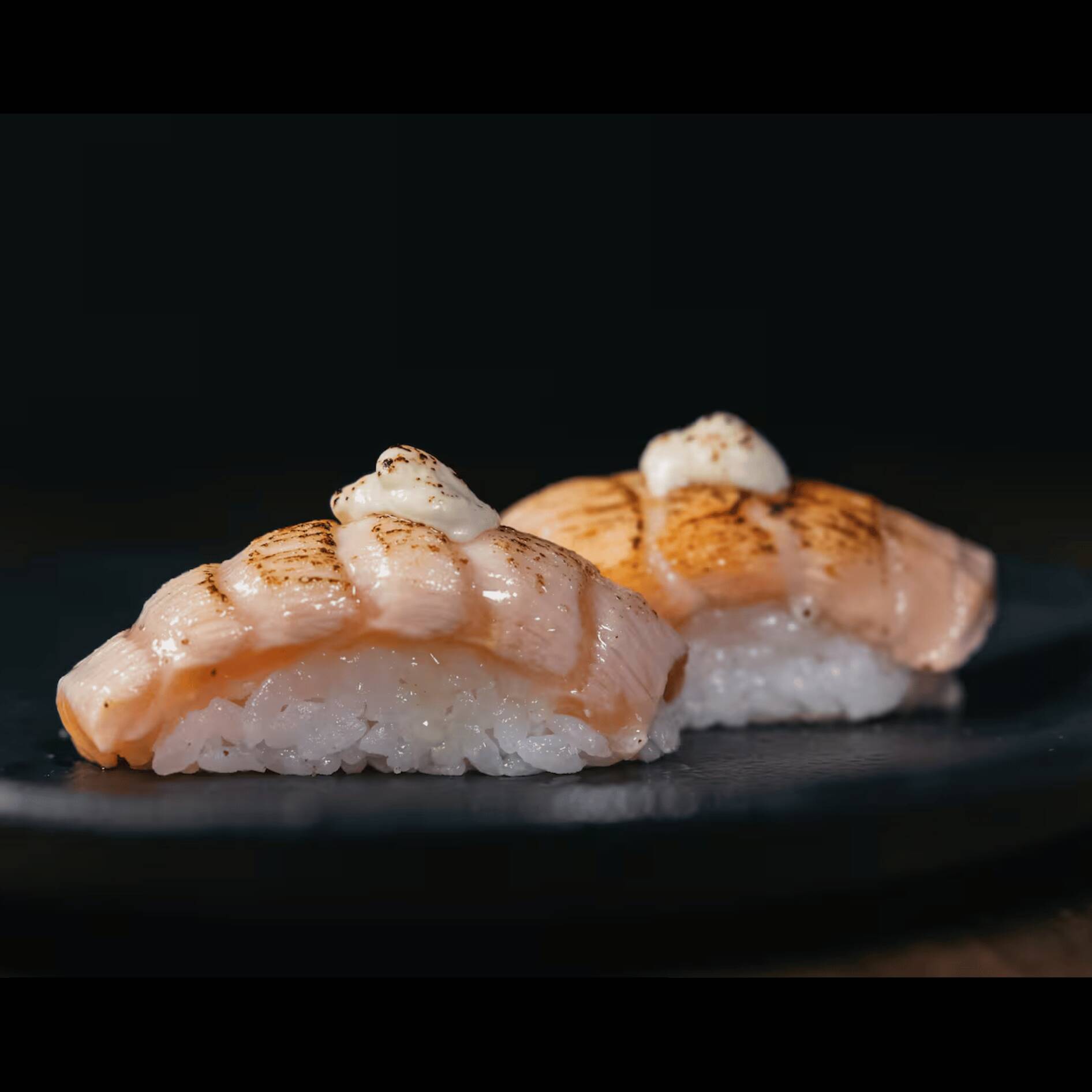 Delicada fatia de salmão fresco sobre o arroz shari, maçaricado e finalizado com alho poró moldado a mão.