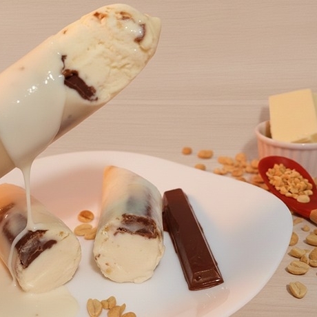 Creme condensado sabor baunilha, coberto com uma camada crocante de chocolate branco, salpicado com amendoim e uma irresistível barrinha de chocolate.