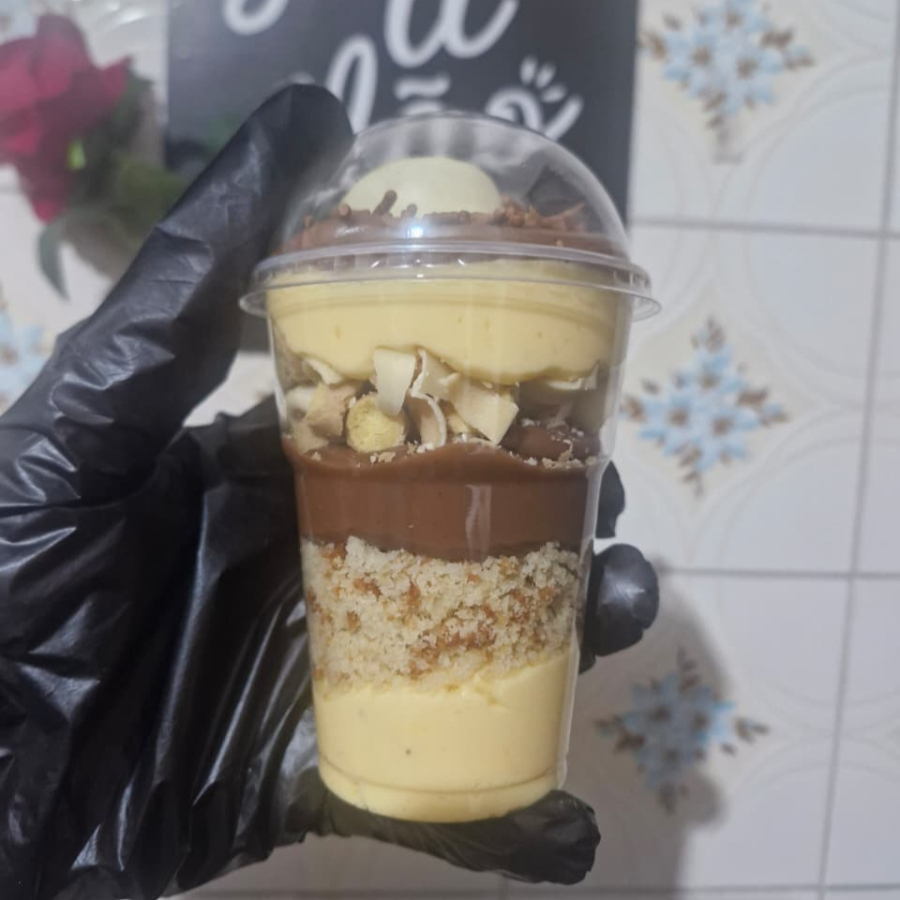 Um delicioso copo, com 3 camadas de mousse, 2 camadas de bolo de baunilha finalizado com maracujá e chocolate Ouro Branco