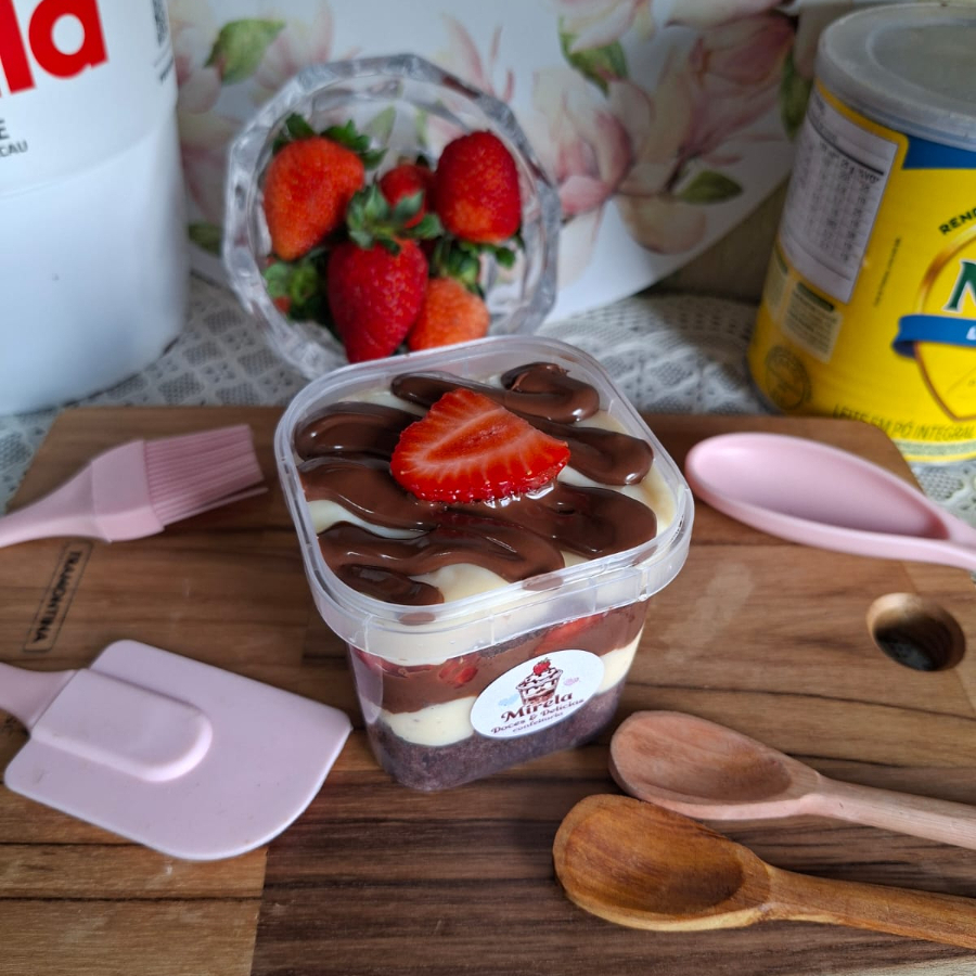 Este irresistível Bolo no Pote pesa 220 gramas e apresenta uma delicada massa chocolate, que serve como base para um recheio incrivelmente cremoso de Leite Ninho. Este creme é generosamente entrelaçado com morangos frescos, trazendo um toque de acidez que equilibra perfeitamente a doçura do prato. Para finalizar, uma camada irresistível de Nutella adiciona um toque indulgente de chocolate. Este é o nosso 'Ninho com Morango e Nutella', uma sobremesa que promete deleitar o seu paladar.
