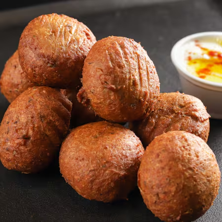 8 unidades de bolinho de grão de bico, com ervas, especiarias (com um toque de pimenta) e molho de iogurte.