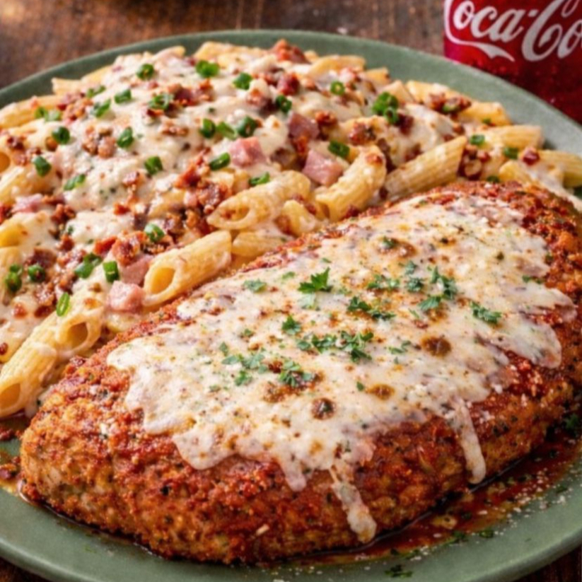 Parmegiana de Frango com Macarrão Paulistano. Uma experiência completa no prato: frango à parmegiana supermacio, coberto com molho artesanal e queijo, Acompanha um macarrão cremoso ao molho branco, misturado com presunto e bacon douradinho. Finalizado com uma camada generosa de queijo derretido e cebolinha fresca. Sabor intenso, cremosidade e aquele toque caseiro que dá vontade de repetir!