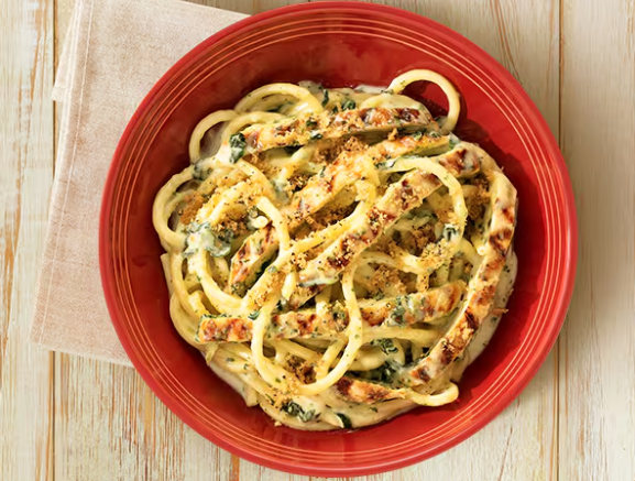 Bucatini ao molho Alfredo com espinafre, acompanhado de frango grelhado e finalizado com farofa especial da casa.