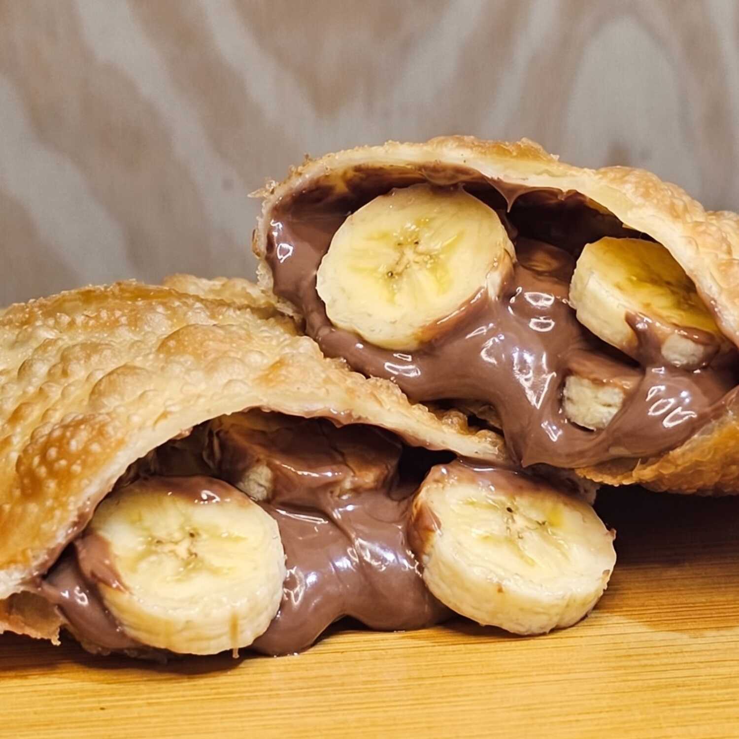 Delicioso pastel recheado com banana e chocolate derretido, uma combinação perfeita de doçura e crocância.