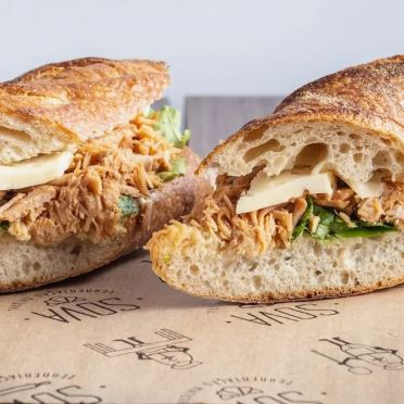 Porco na cachaça desfiado, queijo serra da canastra meia cura, rúcula e maionese da casa na mini baguete