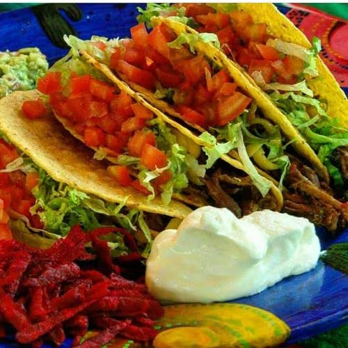 Três crocantes tortillas de milho abertas em meia lua, recheada com queijo, alface e tomate.