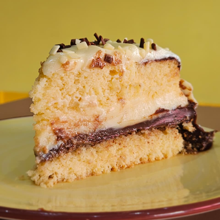 Massa fofinha, úmida, e bem molhadinha, recheado e coberto, com brigadeiro branco e brigadeiro 50% cacau, finalizado com granule de chocolate ao leite, e granule de chocolate branco.
