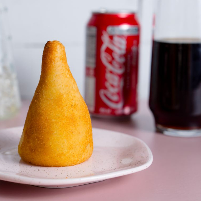 Uma deliciosa coxinha recheada com frango temperado no ponto. Acompanha uma Coca-Cola geladinha.