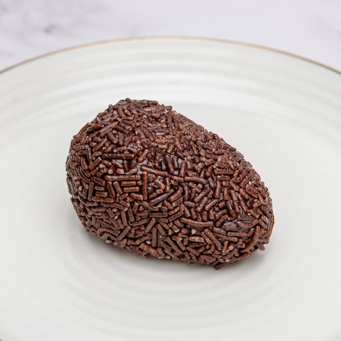 Brigadeiro de cacau recheado com Morango fresco, finalizado com granulados.