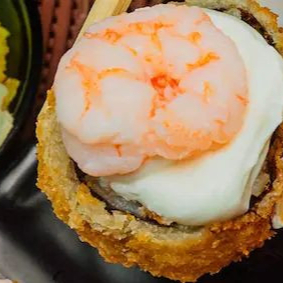 Hotroll empanado e frito, com recheio como salmão e cream cheese, finalizado com um camarão e cream cheese na p0ate de cima do hot, resultando em uma textura crocante por fora e macia por dentro. Nao eixando de fora nossa Cebolinha.