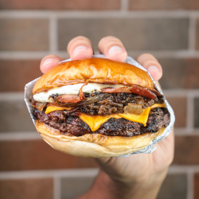 Pão brioche selado na manteiga, com um suculento blend bovino de 180g, queijo cheddar, cebola caramelizada, bacon e molho da casa.