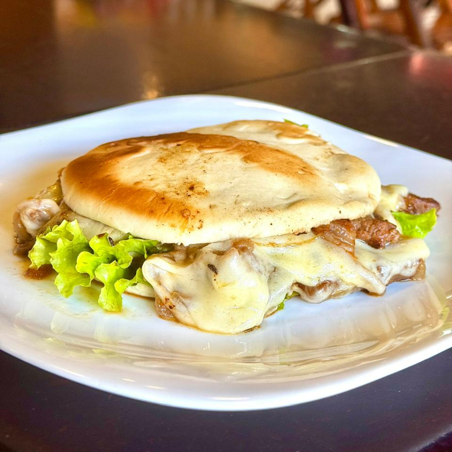 Pão Sírio com Iscas de Carne - 370gr. Este prato é uma combinação sublime de iscas de contrafilé, cuidadosamente grelhadas na chapa, com a suavidade do pão sírio. Os tomates e cebolas, também grelhados, adicionam um toque especial ao prato, realçando a explosão de sabores. A mussarela derretida traz uma textura aveludada e o alface acrescenta frescor à refeição. Para finalizar, nosso exclusivo molho verde dá o toque final, tornando essa experiência culinária inesquecível. Experimente!