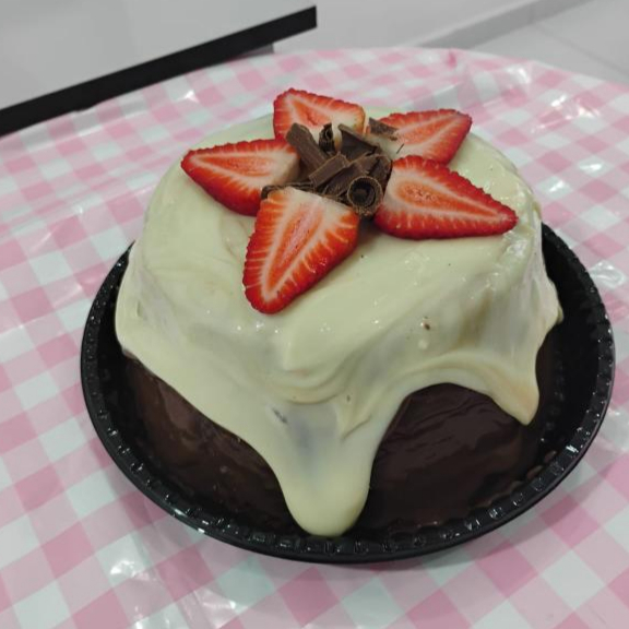 massa deliciosa de chocolate, recheado no meio com brigadeiro cremoso de ninho e pedaços de morango. e brigadeiro de chocolate em volta, com decoração de raspas de chocolate e morango. 1kg de pura gostosura