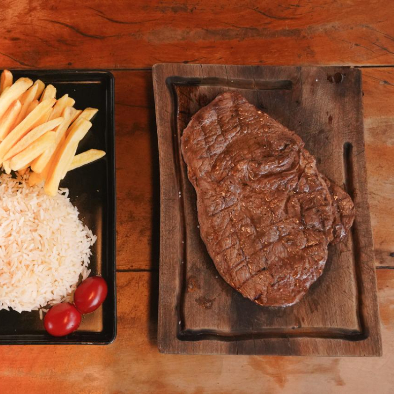 Acompanha Arroz branco, feijão, farofa da casa, fritas e salada.