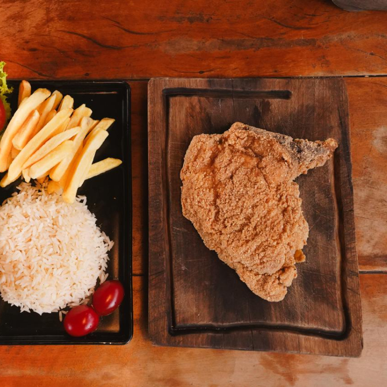 Acompanha Arroz branco, feijão, farofa da casa, fritas e salada.