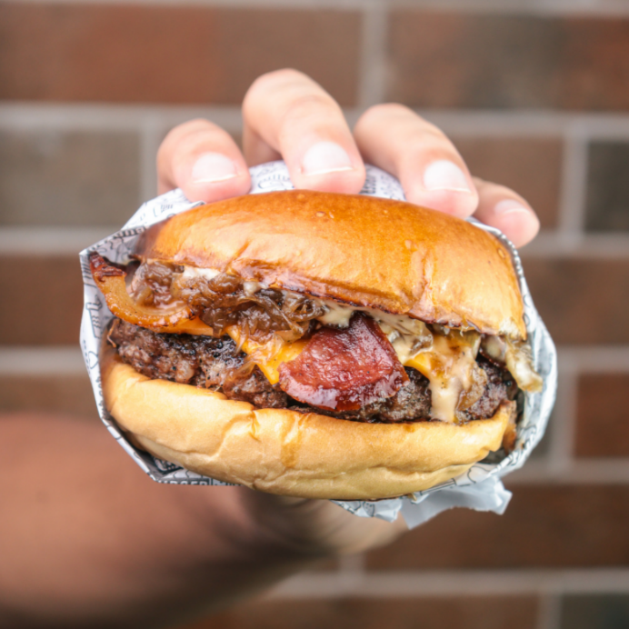 Pão brioche selado na manteiga, com um suculento blend bovino de 180g, queijo cheddar, cebola caramelizada, bacon, calabresa, e molho da casa.