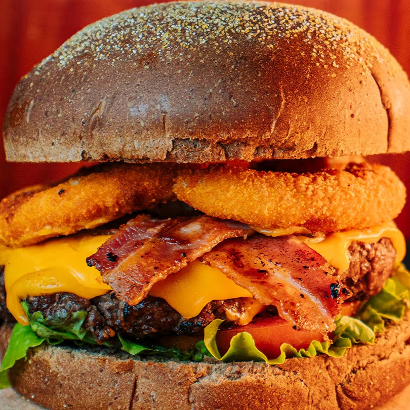 Black Costela Burger feito com hambúrguer de costela de 150g, cheddar fatiado, bacon crocante, cebola empanada, alface, tomate e molho barbecue, tudo no pão australiano. Uma explosão de sabores defumados e irresistíveis!