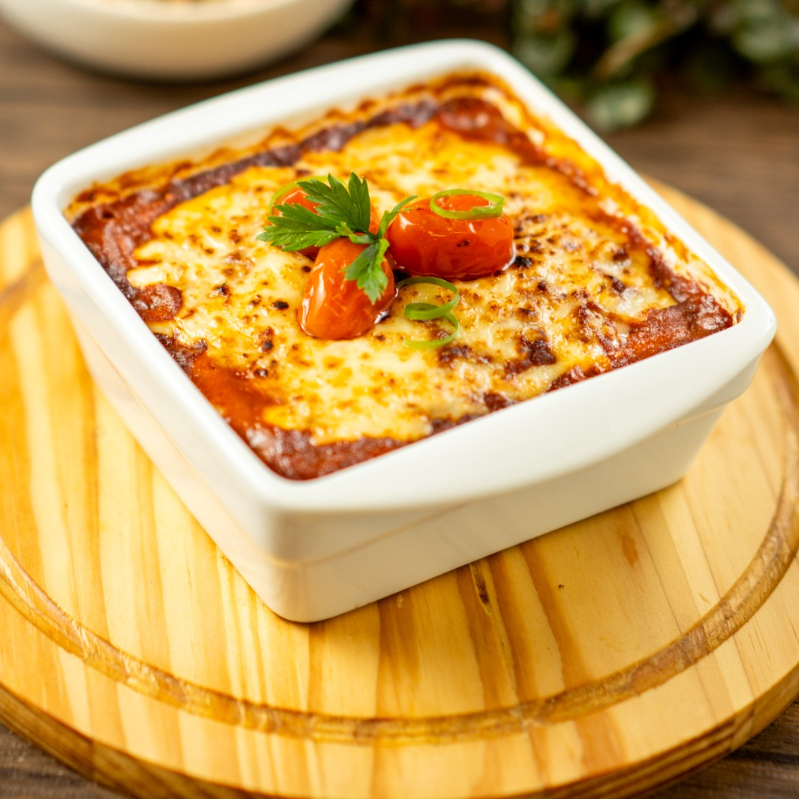 Gratinado de bolo de macaxeira salgado com carne de panela desfiada e molho de tomate.