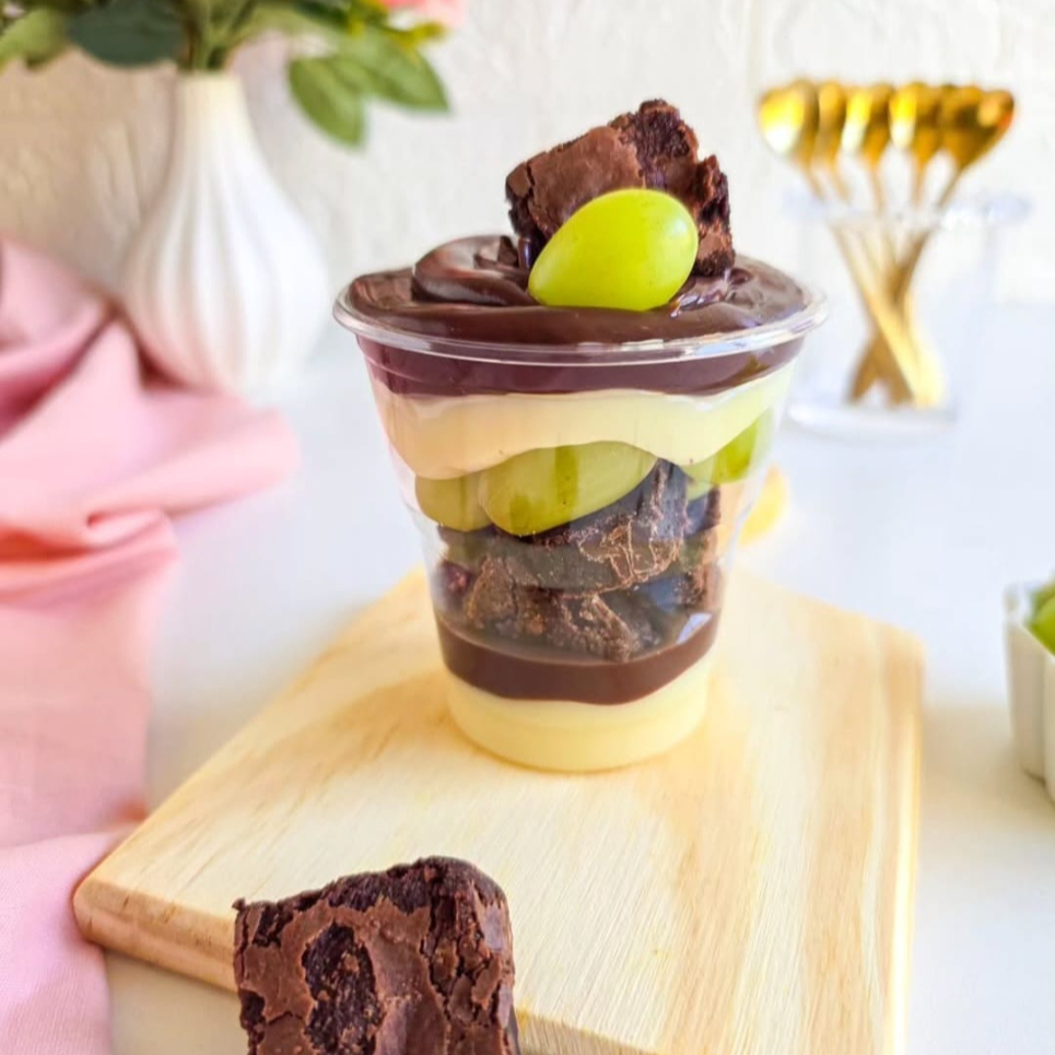 Camadas de creme de ninho e creme de avelã com pedaços de brownie e uva verde sem semente.