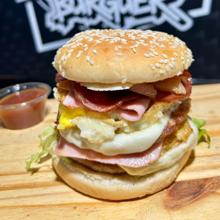 Pão, 2 carnes, 2 ovos, bacon, calabresa, queijo, presunto e alface, maionese temperada e ketchup vao separados em sache .