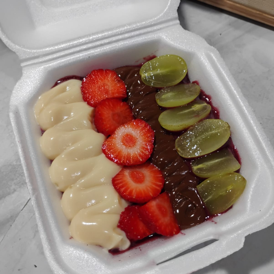 Açaí batido com morango, com morango fruta, uvas, creme de ninho e Nutella Original. Vasilha H01. Serve 01 pessoa.