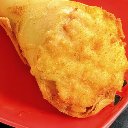 Temaki com massa de harumaki, recheado de salmão cru, cream cheese e cebolinha.