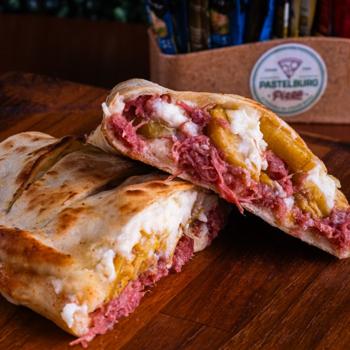 O Calzone Nordestino com Banana e Catupiry é a estrela das nossas 'Ofertas Exclusivas'. Este prato celebra a rica culinária nordestina, com um recheio irresistível de charque desfiada, cuidadosamente refogada para realçar seu sabor autêntico. Acompanha a suculenta banana da terra, frita à perfeição, conferindo uma doçura equilibrada que harmoniza com o sabor robusto da charque.