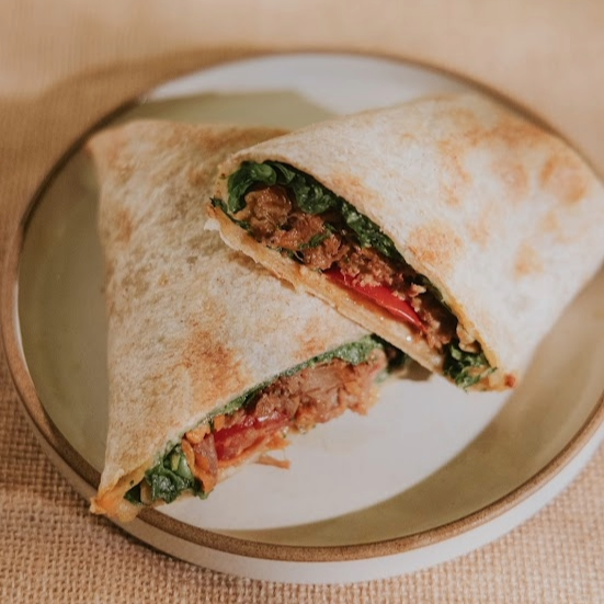 Tortilla integral, requeijão cremoso, rúcula mini, ragu de carne, tomate grape, cenoura, relish de cebola roxa e molho pesto.